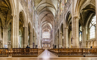 Interior view of Basilica of Saint-Denis with vaulted ceilings and stained glass windows.