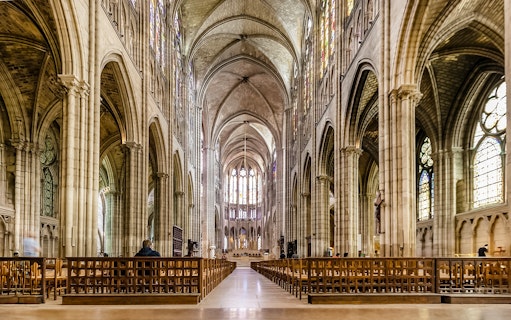 Interior view of Basilica of Saint-Denis with vaulted ceilings and stained glass windows.