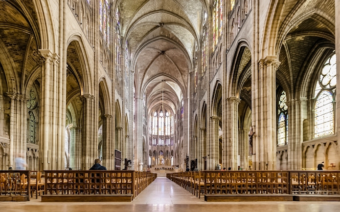 Interior view of Basilica of Saint-Denis with vaulted ceilings and stained glass windows.