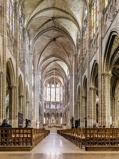 Interior view of Basilica of Saint-Denis with vaulted ceilings and stained glass windows.