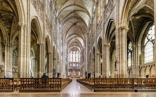 Interior view of Basilica of Saint-Denis with vaulted ceilings and stained glass windows.