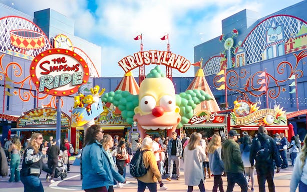 Krustyland entrance at Universal Studios Orlando with The Simpsons Ride sign and visitors.