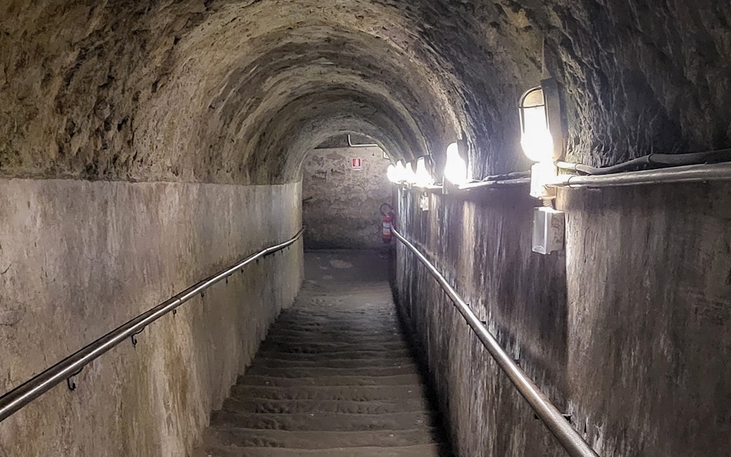 Staircase leading to Naples underground city, dimly lit tunnel with stone walls.