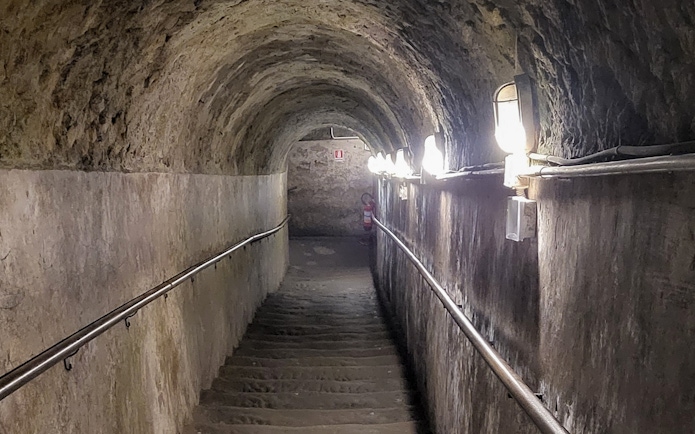 Staircase leading to Naples underground city, dimly lit tunnel with stone walls.