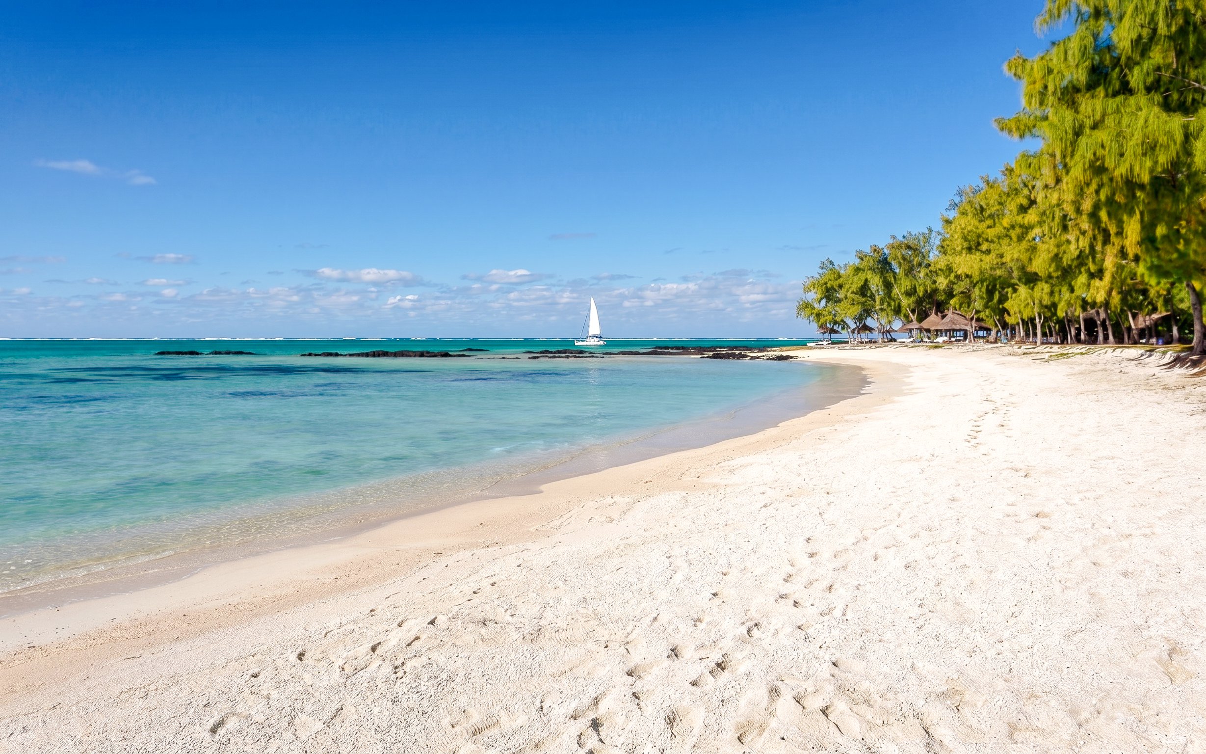 Sandy beach with turquoise water and sailboat at Ile Aux Cerf, Mauritius.