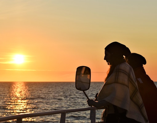 Visitor on deck during Reykjavik Classic Whales tour at sunset.
