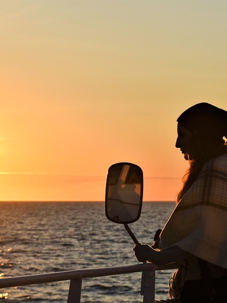 Visitor on deck during Reykjavik Classic Whales tour at sunset.