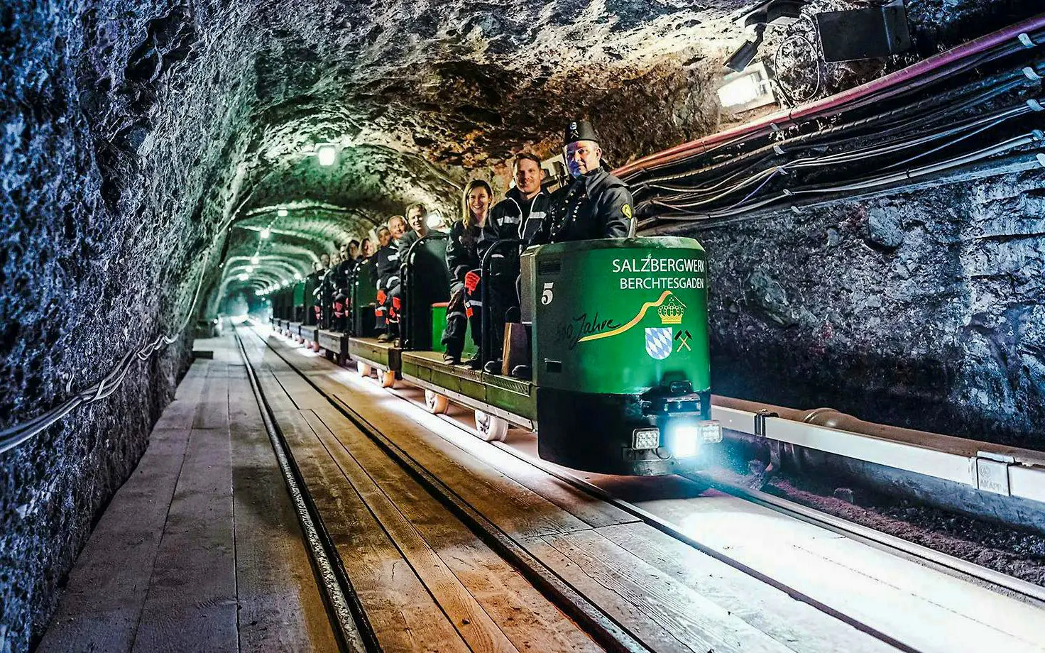 Mine train tour inside Berchtesgaden Salt Mine with visitors seated.