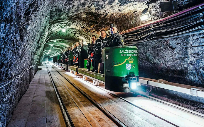Mine train tour inside Berchtesgaden Salt Mine with visitors seated.