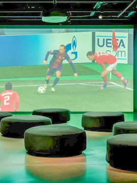 Interactive seating area with a large screen showing a soccer match at Iniesta Experience, Spain.
