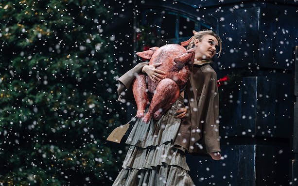 Person holding a large turkey in a snowy scene from A Christmas Carol.