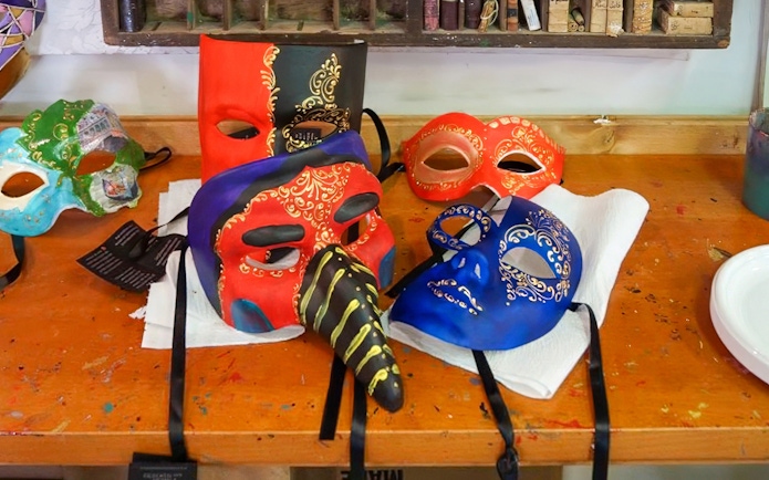 Colorful Venetian masks on a workshop table for a mask painting activity.