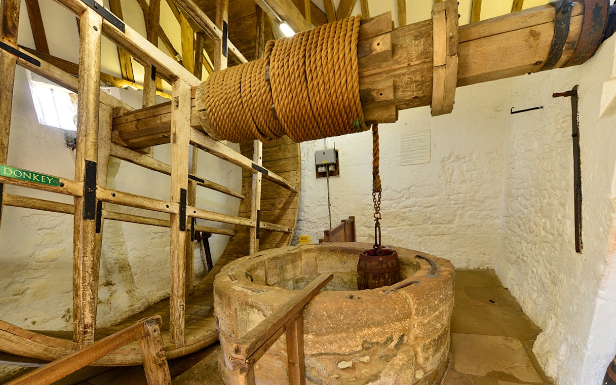 Carisbrooke Castle well house with historic wooden wheel and rope mechanism.