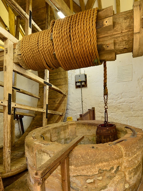 Carisbrooke Castle well house with historic wooden wheel and rope mechanism.