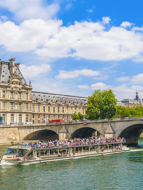Seine River cruise boat passing by the Louvre Museum in Paris.
