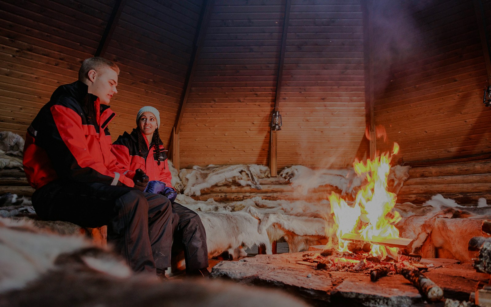 Couple sitting by a fire inside a Finnish kota in Rovaniemi.