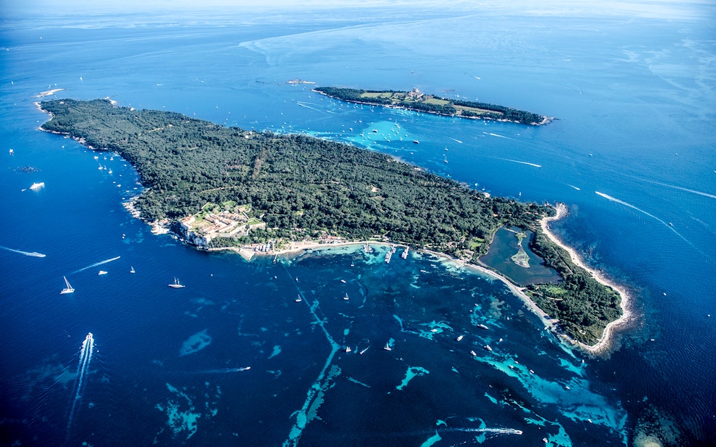 Aerial view of an island with lush greenery and surrounding blue waters seen from Nice sightseeing cruise.