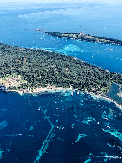Aerial view of an island with lush greenery and surrounding blue waters seen from Nice sightseeing cruise.
