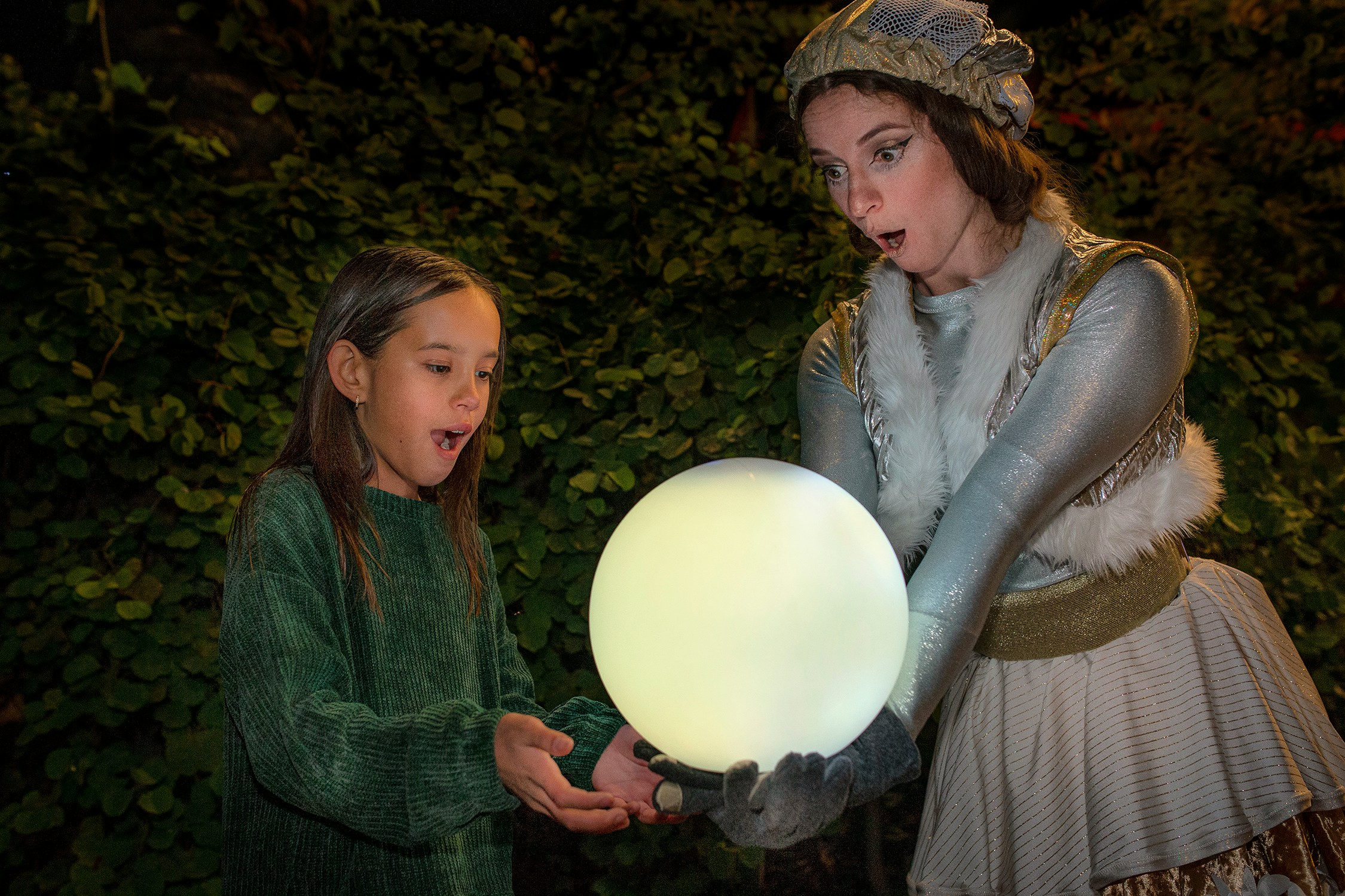 Child and performer with glowing orb at San Diego Zoo Aurora event.