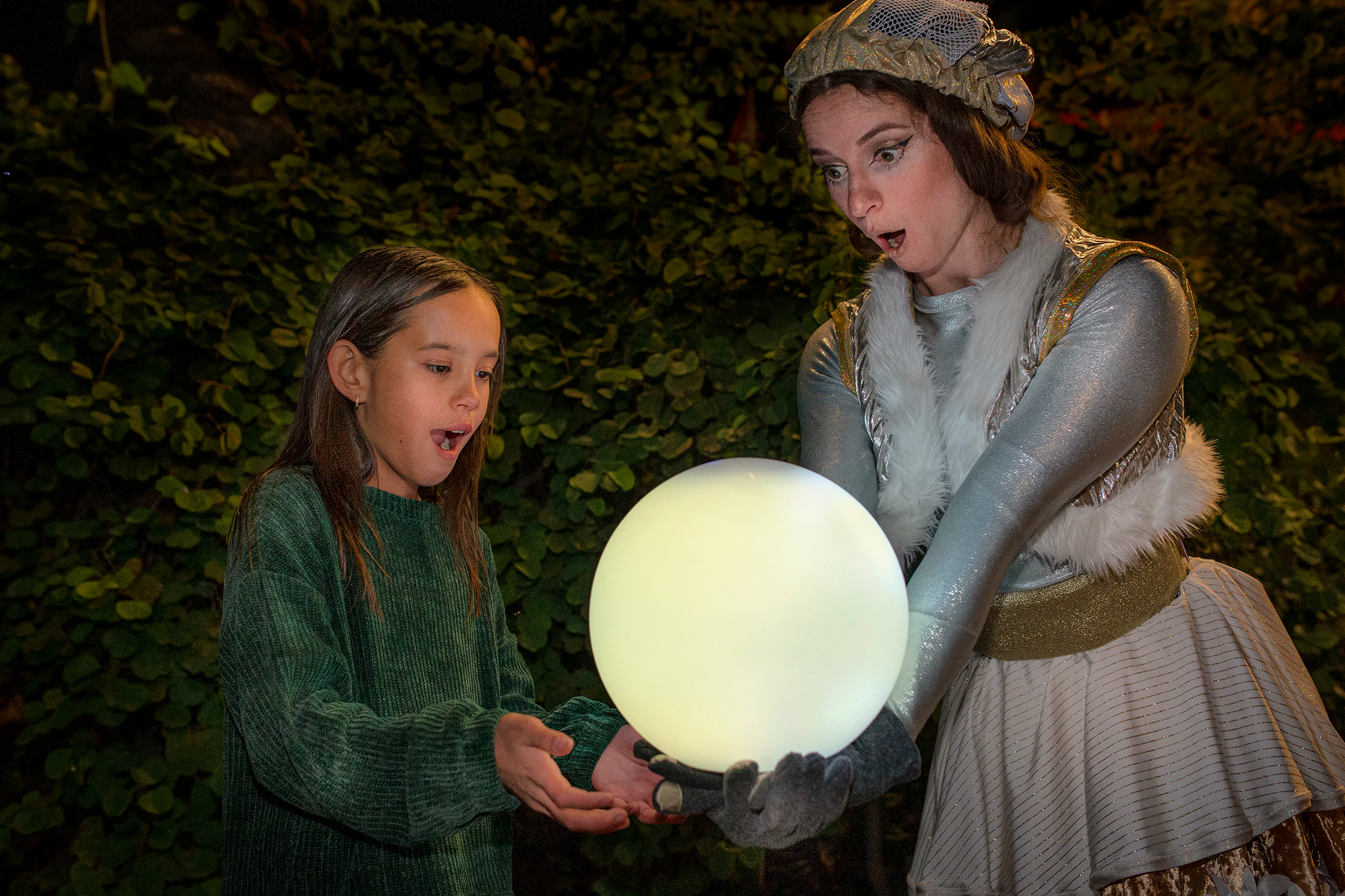Child and performer with glowing orb at San Diego Zoo Aurora event.