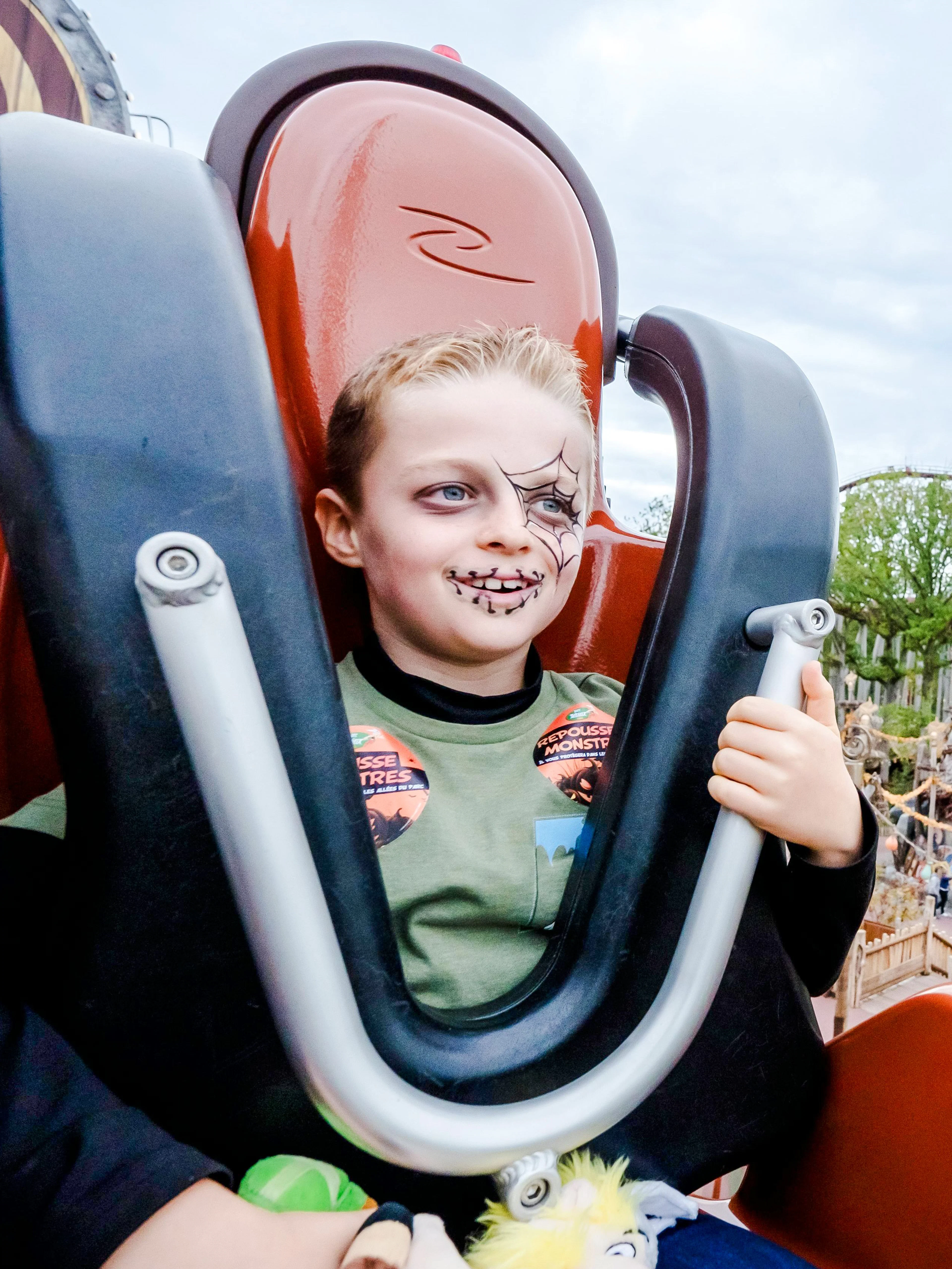 Child with Halloween face paint on a roller coaster at Parc Asterix, Paris, France.