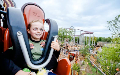Child with Halloween face paint on a roller coaster at Parc Asterix, Paris, France.