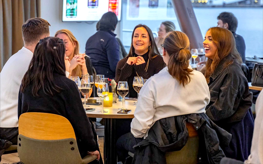 Group enjoying dinner on an Oslo cruise with wine glasses on the table.