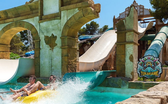 Tukakame water slide ride at Aqualand El Arenal with two people splashing into the pool.