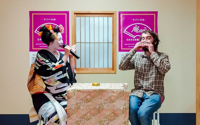 Maiko in traditional attire speaking with a guest during a Q&A session in Japan.