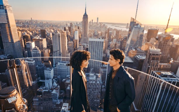 Couple enjoying the view from Top of the Rock, New York City skyline in background.