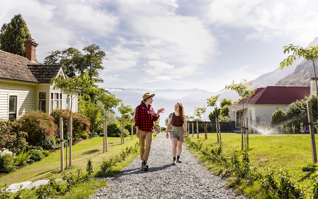 Tourists walking along a path at Walter Peak High Country Farm with scenic views.