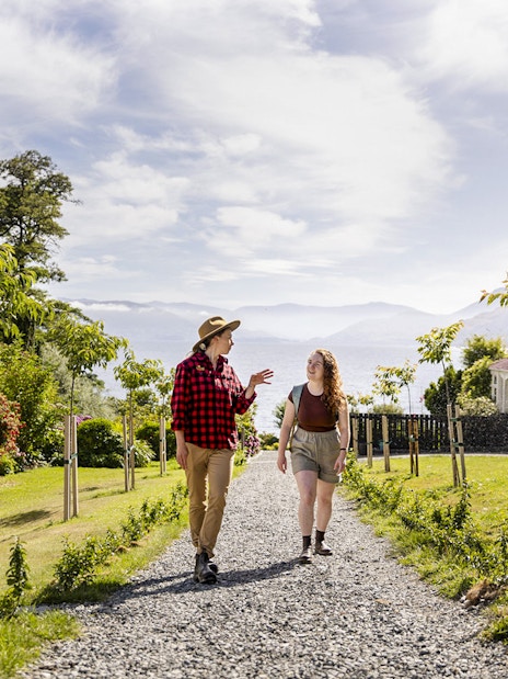 Tourists walking along a path at Walter Peak High Country Farm with scenic views.