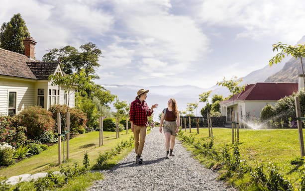 Tourists walking along a path at Walter Peak High Country Farm with scenic views.
