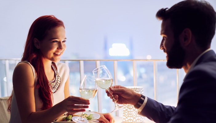Couple dining at a restaurant, toasting with wine glasses.