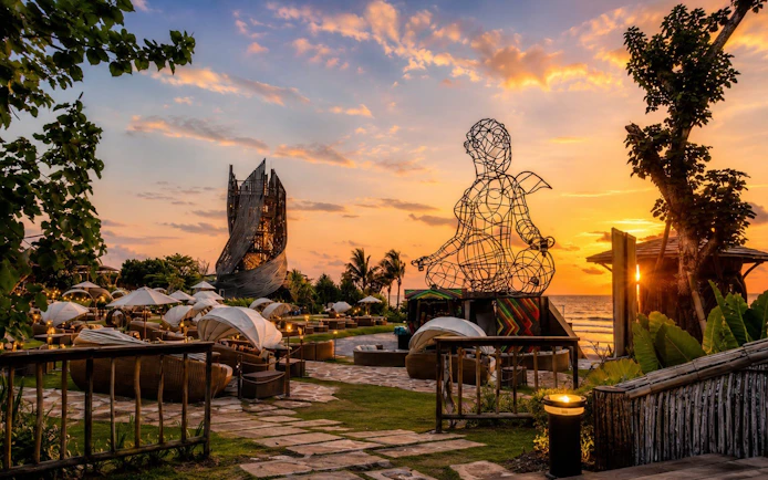 Luna Beach Club at sunset with wire sculpture and ocean view.