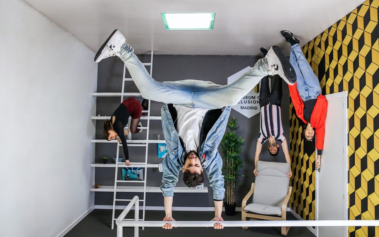 Visitors experiencing an upside-down room at the Museum of Illusions in Madrid.