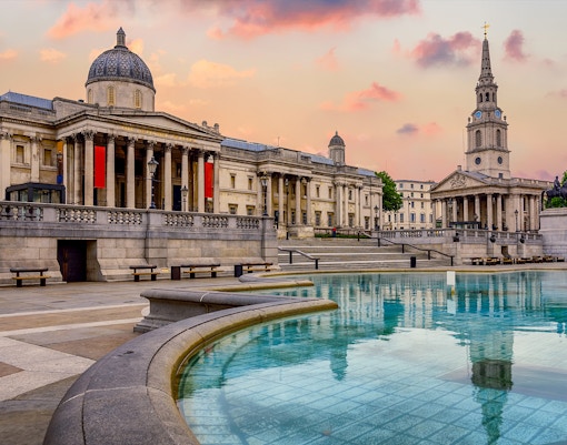National Gallery facade at Trafalgar Square, London, England, with visitors in the foreground.