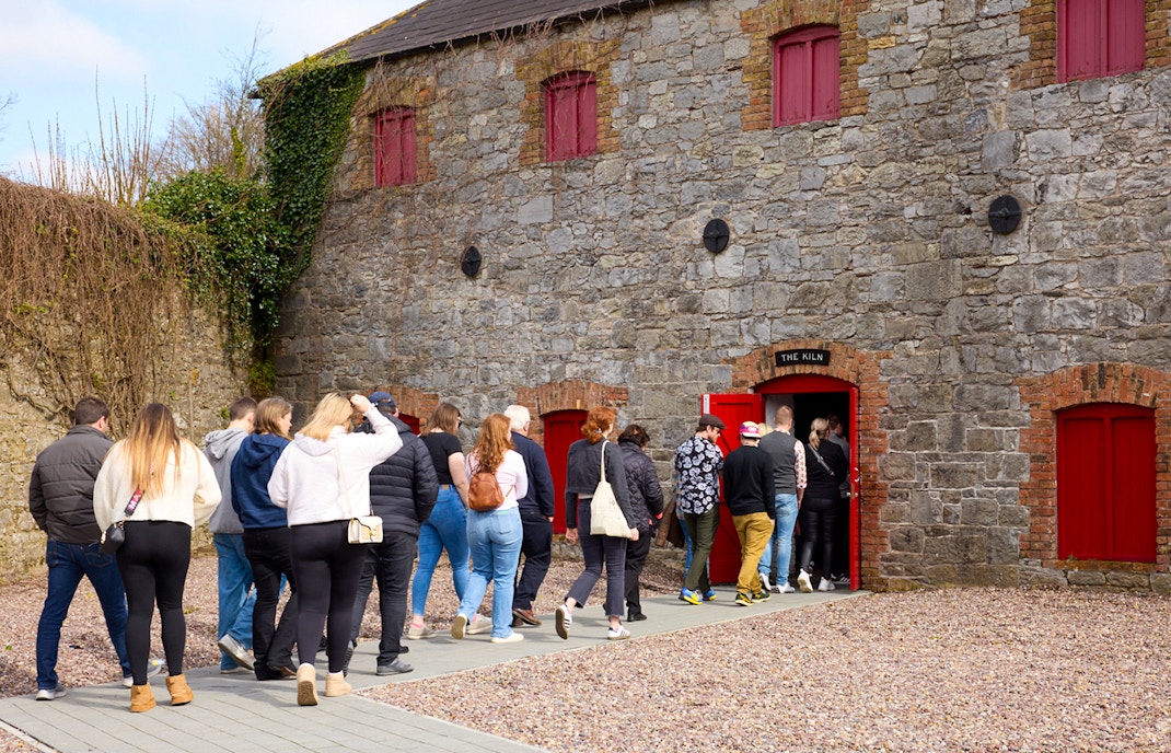 Visitors exploring Midleton Distillery, Ireland, observing whiskey production process.