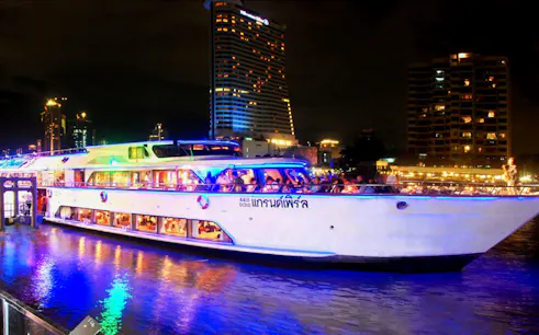 Grand Pearl Dinner Cruise ship illuminated at night on a river in Bangkok.