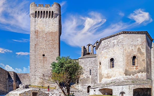 Montmajour Abbey stone tower and chapel under blue sky in Provence, France.