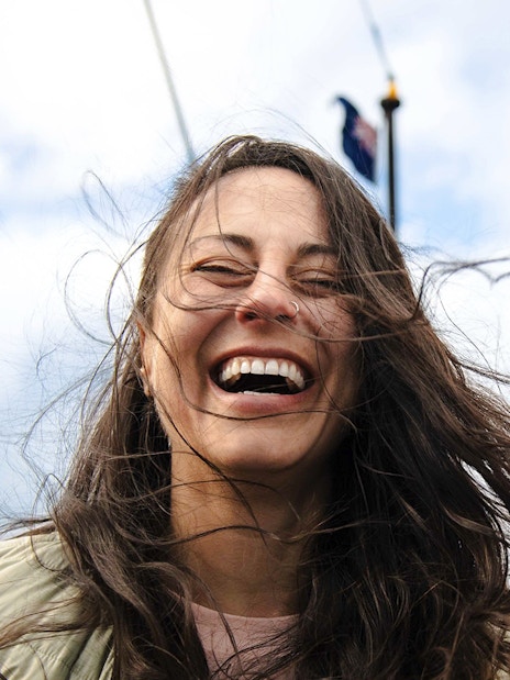 Woman smiling on a boat deck with windblown hair, Queenstown.