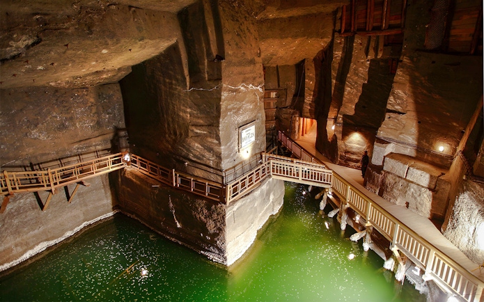 Wieliczka Salt Mine underground salt lake with wooden walkways and illuminated rock walls.