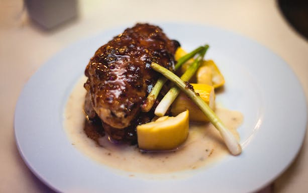 Grilled chicken with sauce and vegetables served on a plate during Boston Odyssey dinner cruise.