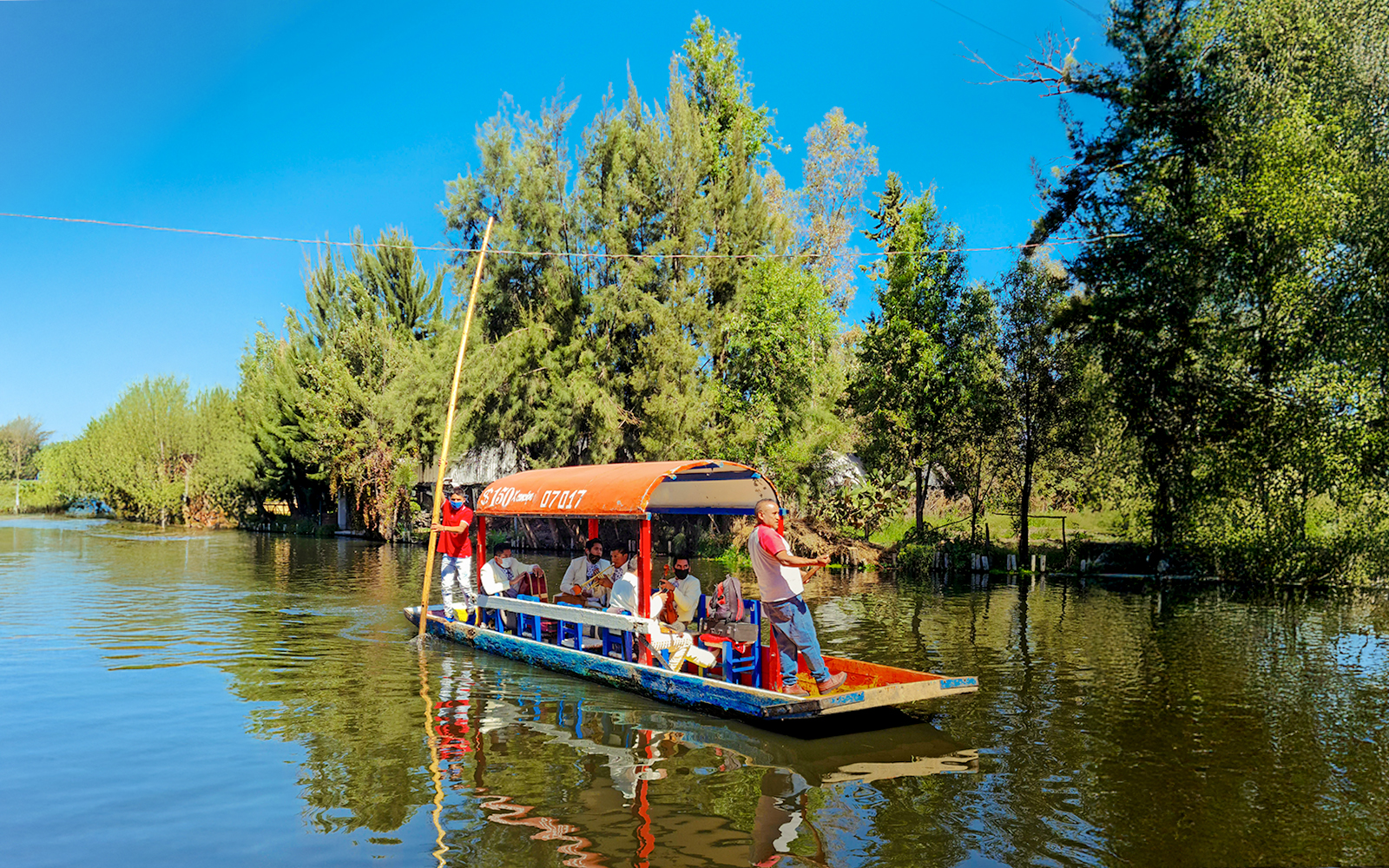 Trajinera boat with people on Xochimilco river, Mexico City.