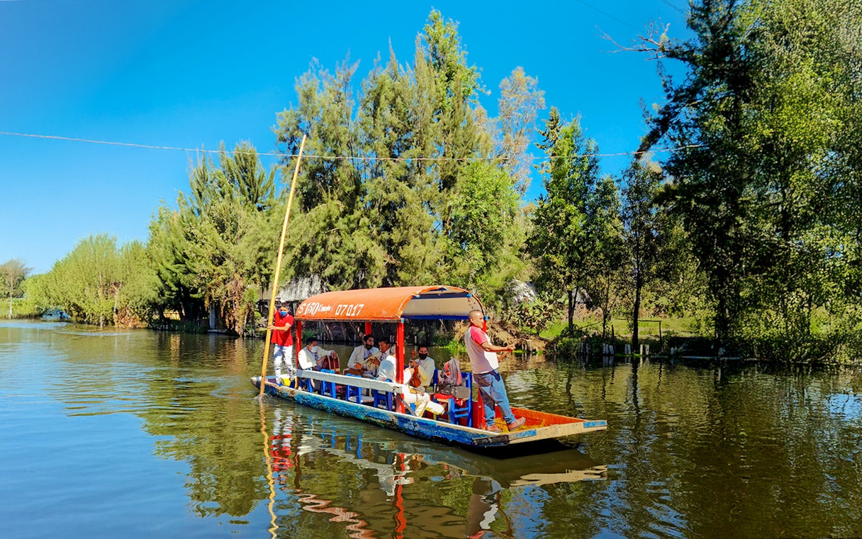 Trajinera boat with people on Xochimilco river, Mexico City.