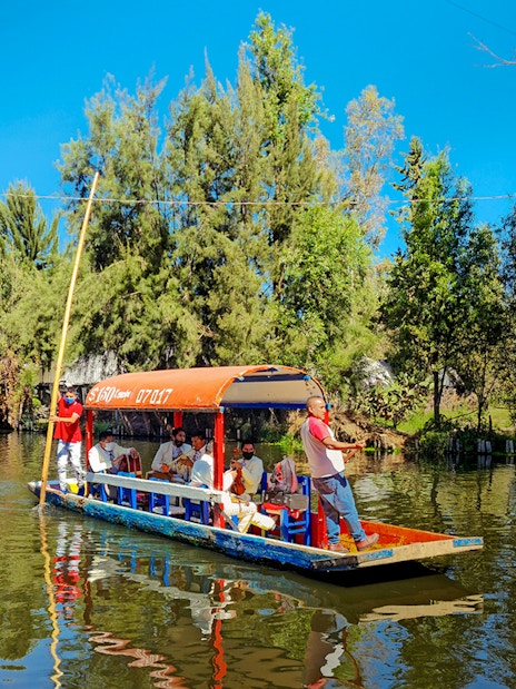Trajinera boat with people on Xochimilco river, Mexico City.