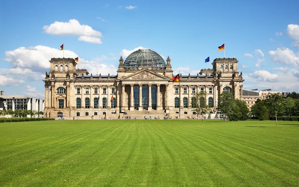 Reichstag building with glass dome in Berlin, Germany, viewed from the lawn.