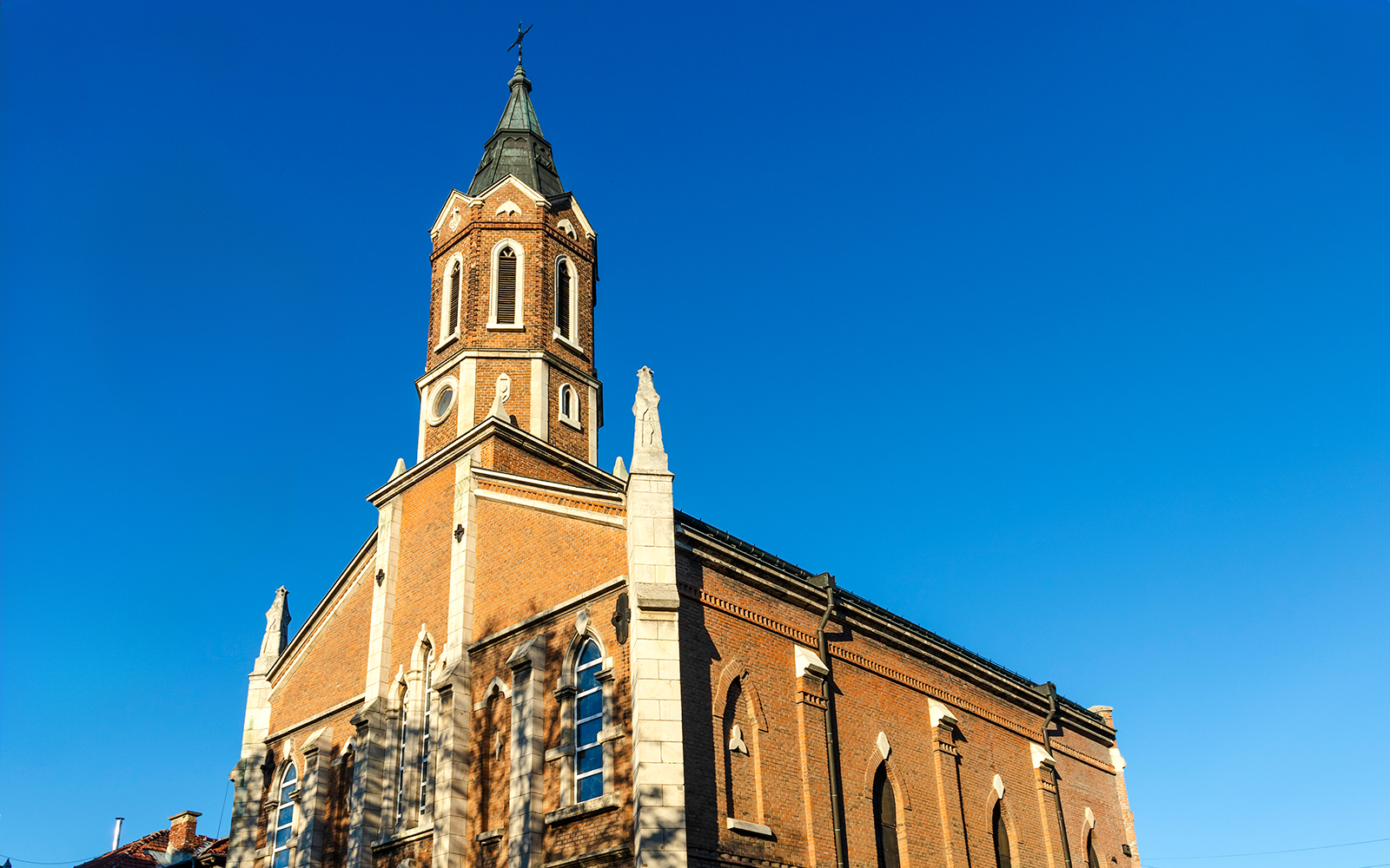 St. Paul's Church in Ruse with its brick facade and tall steeple against a clear blue sky.