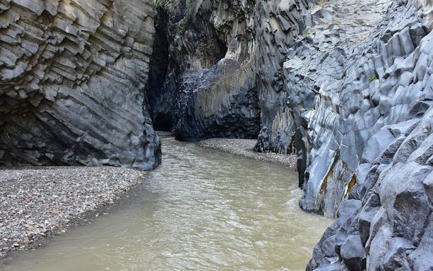 River flowing through rocky gorge on Mount Etna's south side trek.