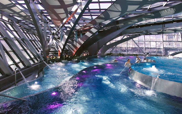 Interior lagoon of Caldea Spa in Andorra with modern architecture and colorful lighting.